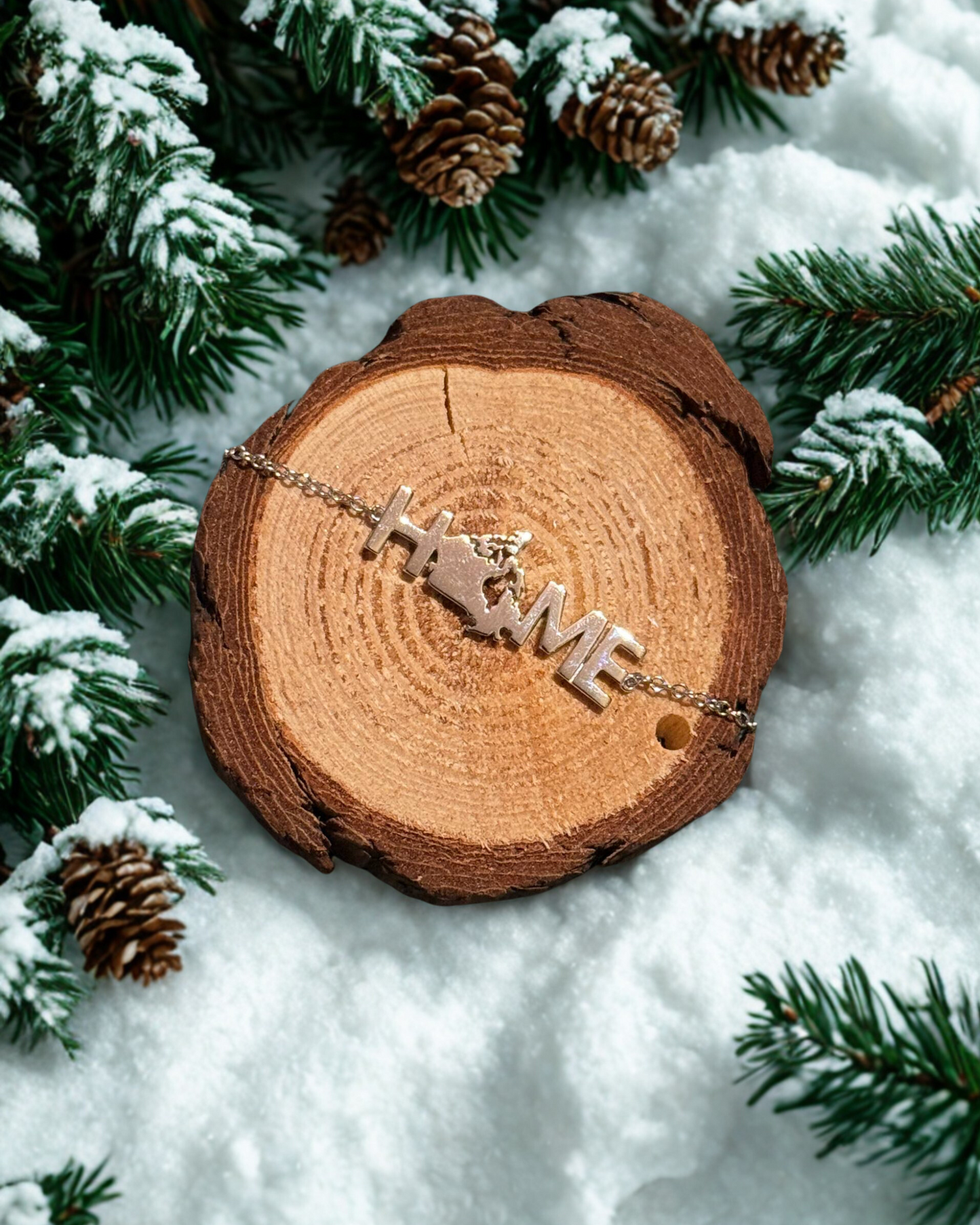 Bracelet with 'HOME' letters on a wooden log surrounded by snow and pine branches